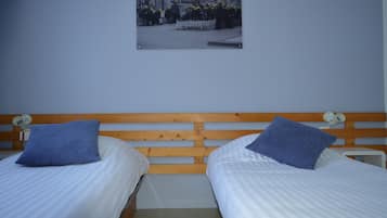 A bedroom with two beds, each with a blue pillow and white bedding.