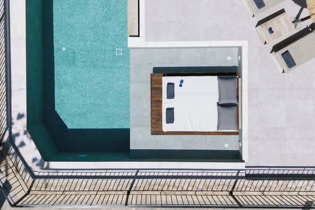 An aerial view of a hotel room with a pool, a bed, and a small seating area.