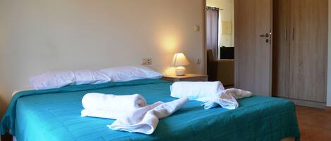 A hotel room with a bed, a nightstand, a lamp, and a wardrobe.
