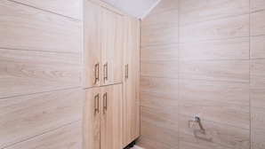 A bathroom with wooden cabinetry and a tiled wall. - Matala Bay Apartments (Faistos)