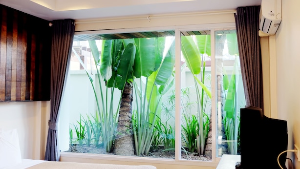 Une chambre d’hôtel avec une grande fenêtre, un lit, une télévision et un appareil de climatisation.