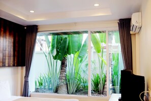 A hotel room with a large window, a bed, a TV, and an air conditioning unit. - Pai In Town (Pai)