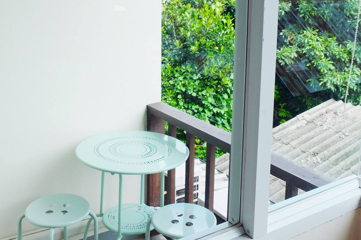 A balcony with a glass door, a small round table, and two chairs.