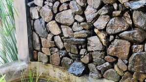 Un mur de pierre avec une petite fontaine à sa base.