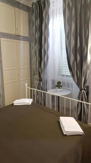 A bedroom with a bed, a small table with a plant, and curtains. - B&B Carpe Diem (Rome)