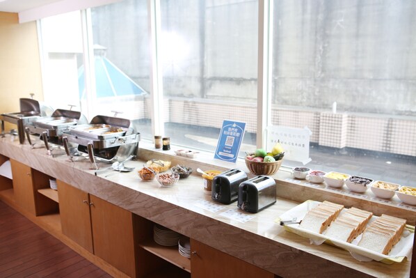 A buffet counter with various food items and a sign indicating a Facebook page.