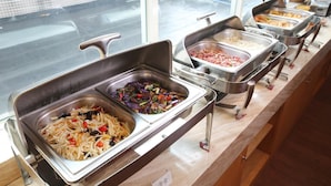 Un buffet proposant une variété de plats, notamment des nouilles, des légumes sautés et des plats de viande.
