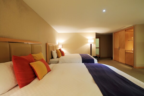 Una habitación de hotel con dos camas, un armario y un escritorio.