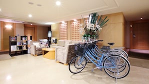 Un hall d’entrée avec un canapé, une table basse, une bibliothèque et un vélo bleu doté d’un panier.