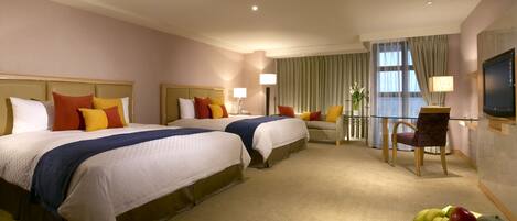 Habitación de hotel con dos camas, un sofá, un televisor y un frutero.