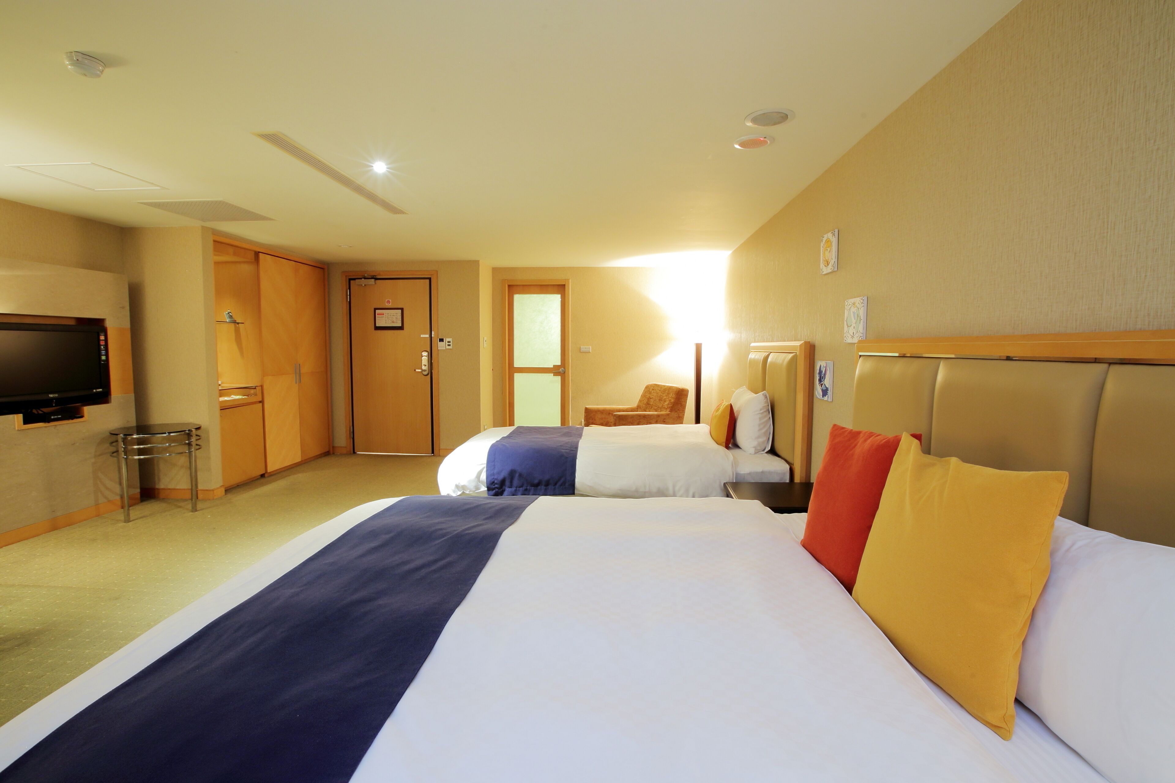 A hotel room with a large bed, a television, a desk, and a chair.