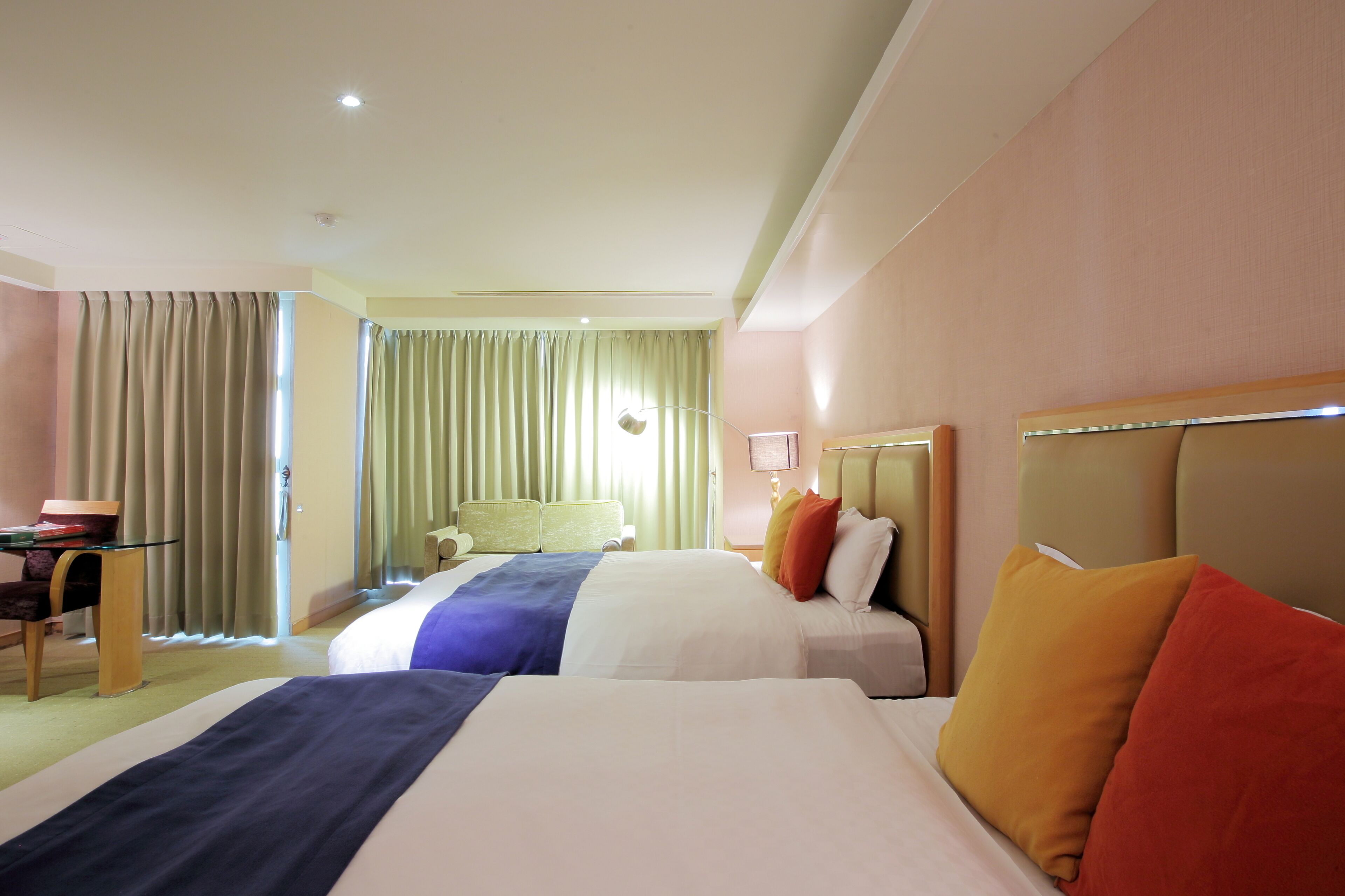 A hotel room with two beds, a desk, and a chair.