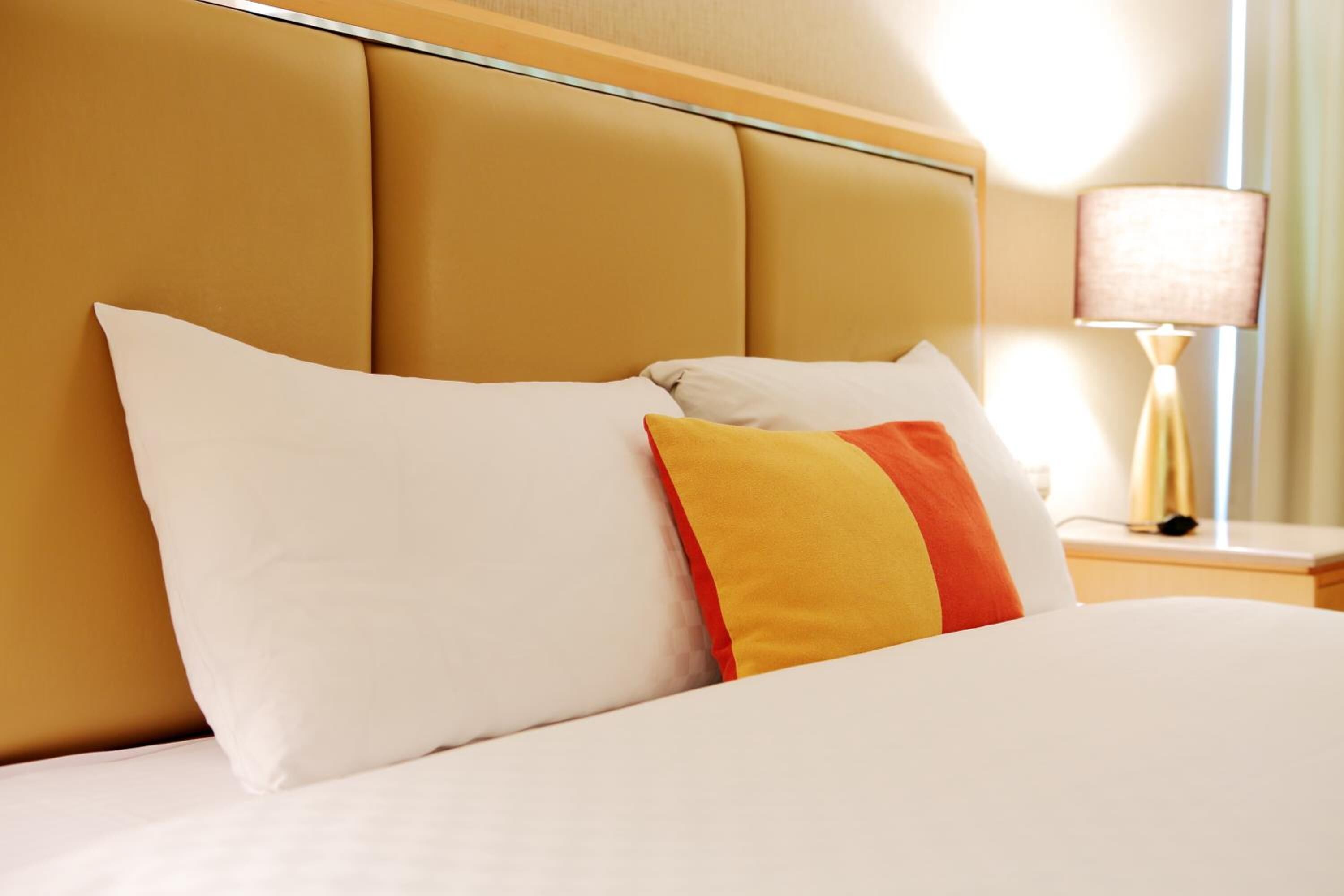 A hotel room with a bed, a nightstand, and a lamp.