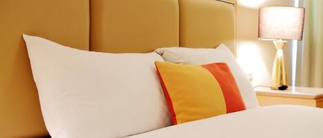 A hotel room with a bed, a nightstand, and a lamp.