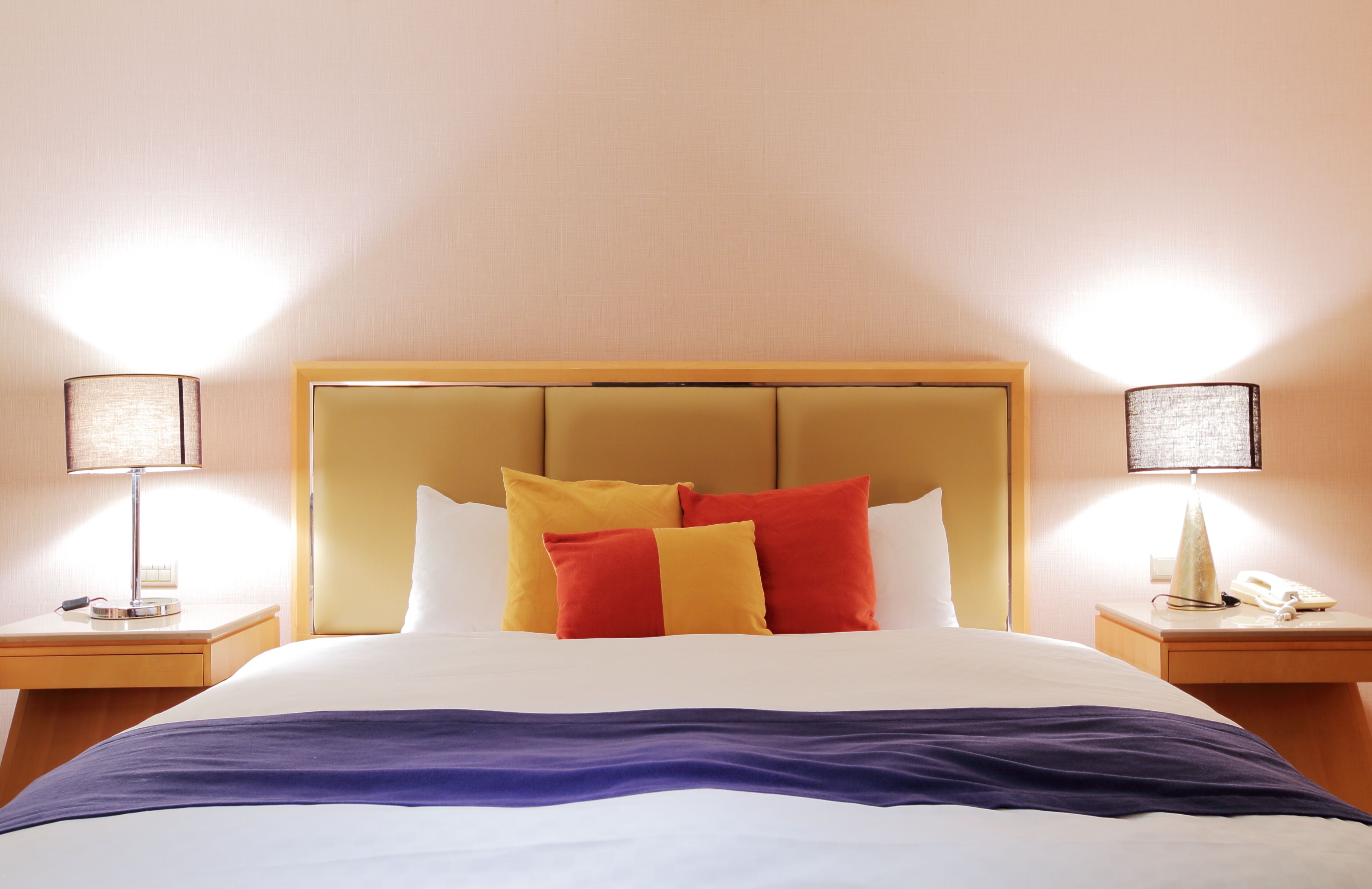 A hotel room with a large bed, two bedside tables, and a headboard.