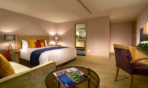 A hotel room with a bed, bedside tables, a desk, a chair, and a round table with a magazine.