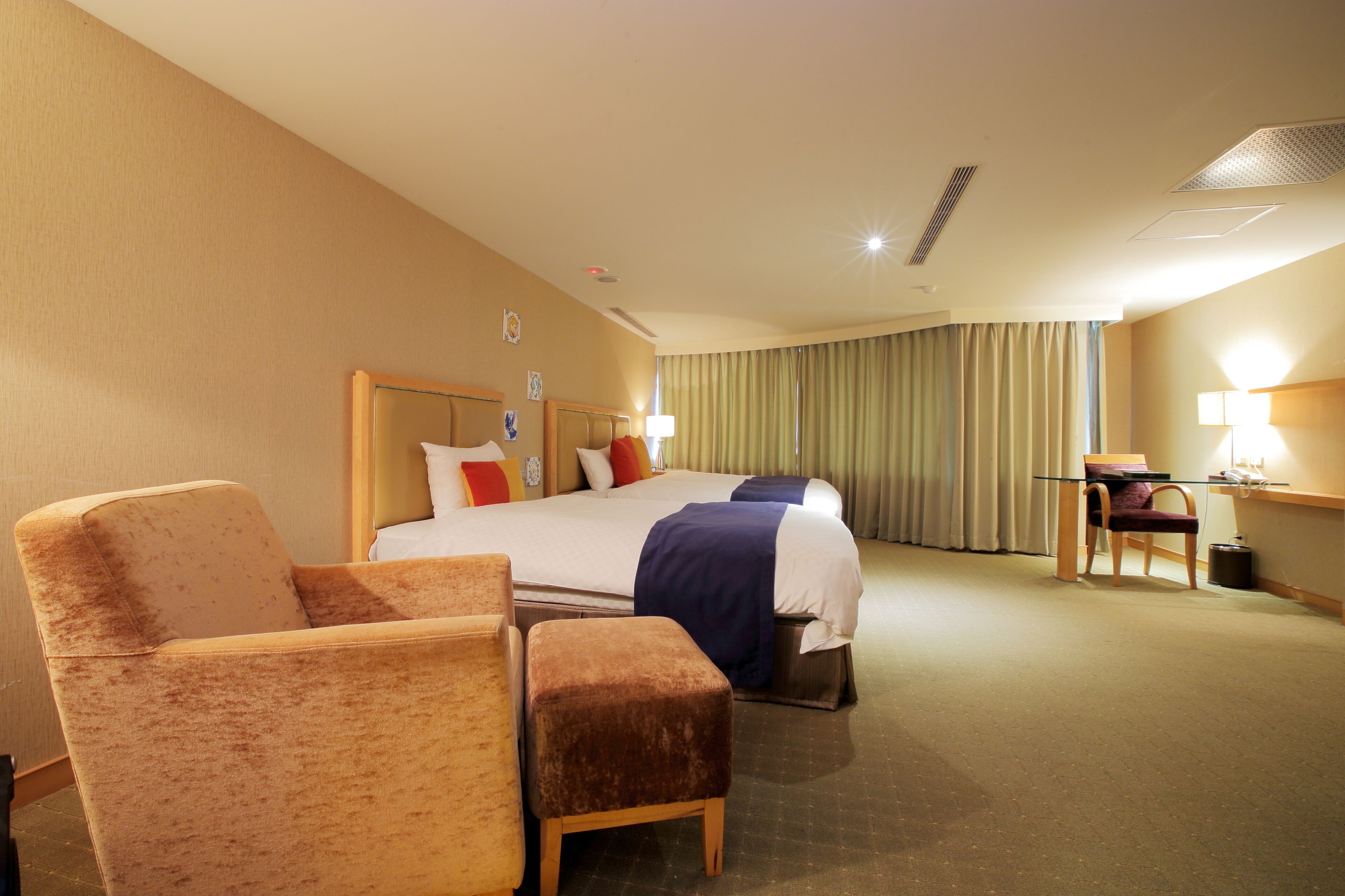 Una habitación de hotel con una cama grande, dos sillones, un escritorio y una lámpara.