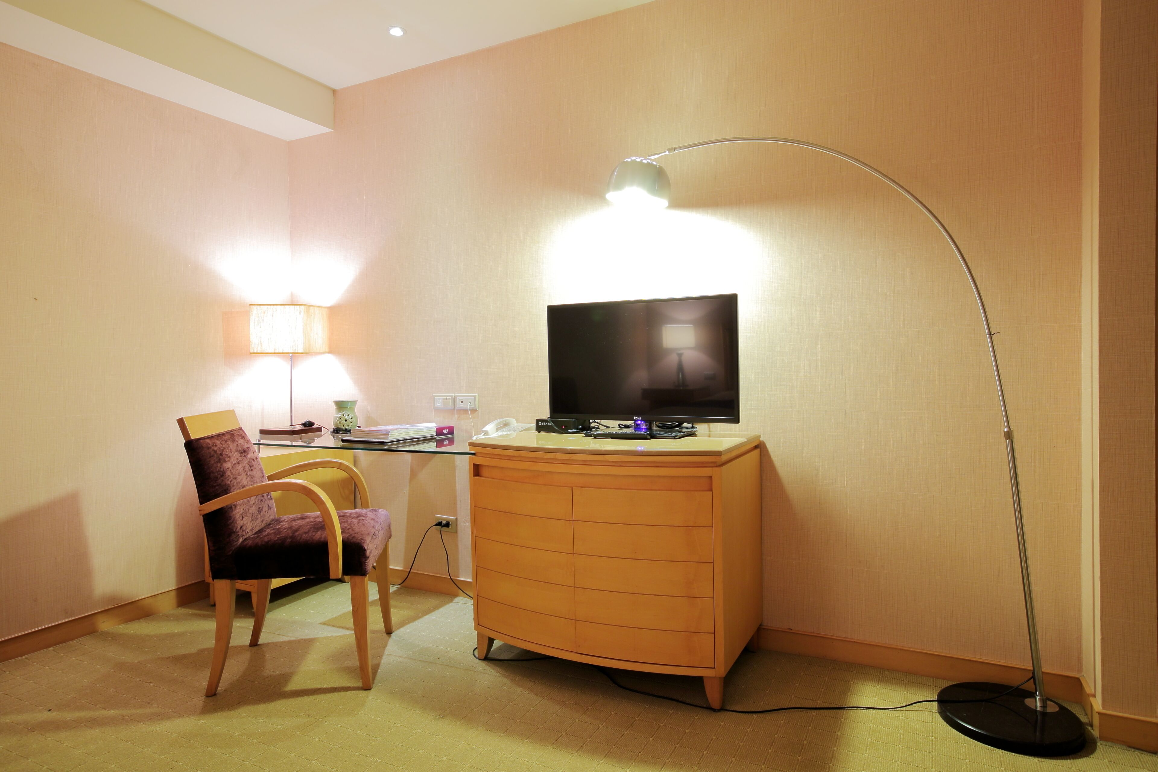 Une chambre d’hôtel équipée d’un bureau, d’une chaise, d’une télévision, d’une lampe et d’une commode.