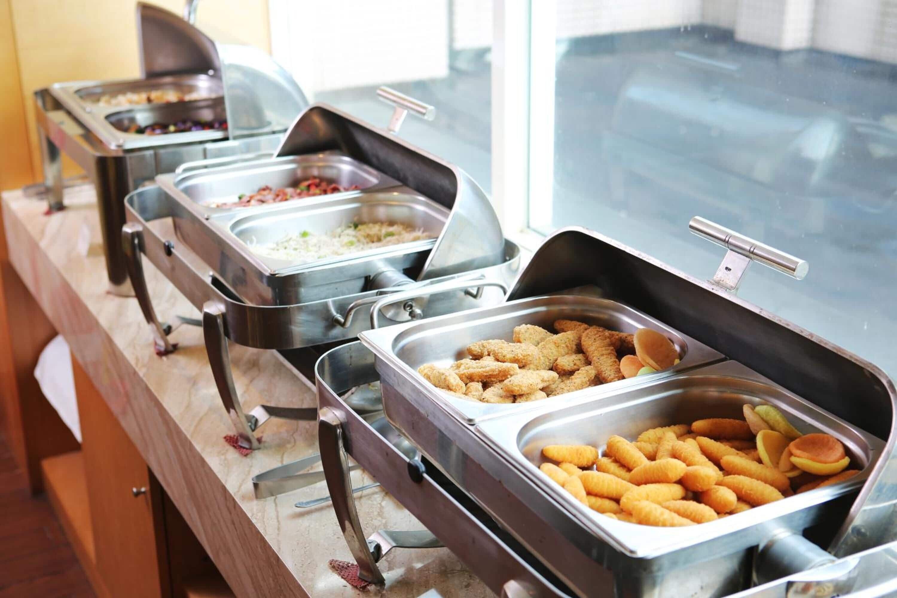 Una barra de buffet con diversos alimentos, como arroz, carne y aperitivos.