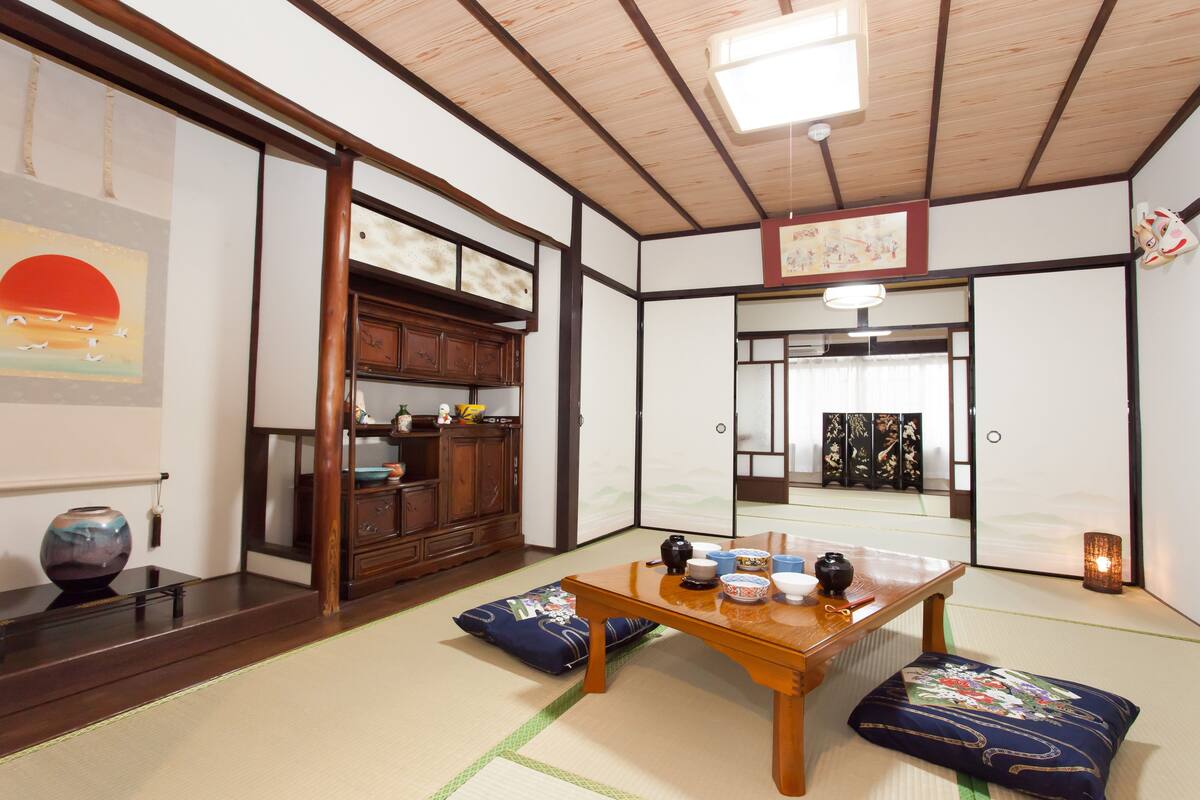 A traditional Japanese room with tatami flooring, a wooden table with tea set, a cabinet, and sliding doors.