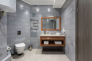 A modern bathroom with grey tiles, a wooden vanity, a mirror, and a toilet. - Twin Apart Hotel (Kyiv)