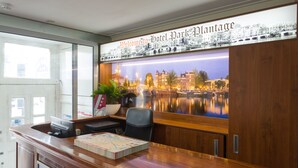 A reception desk with a view of a cityscape, a welcome sign, and a plant. - Hotel Park Plantage (Amsterdam)
