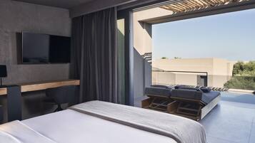 Ein modernes Hotelzimmer mit einem großen Bett, einem Flachbildfernseher an der Wand, einem Schreibtisch mit Stuhl und einem Balkon mit Sitzgelegenheit.