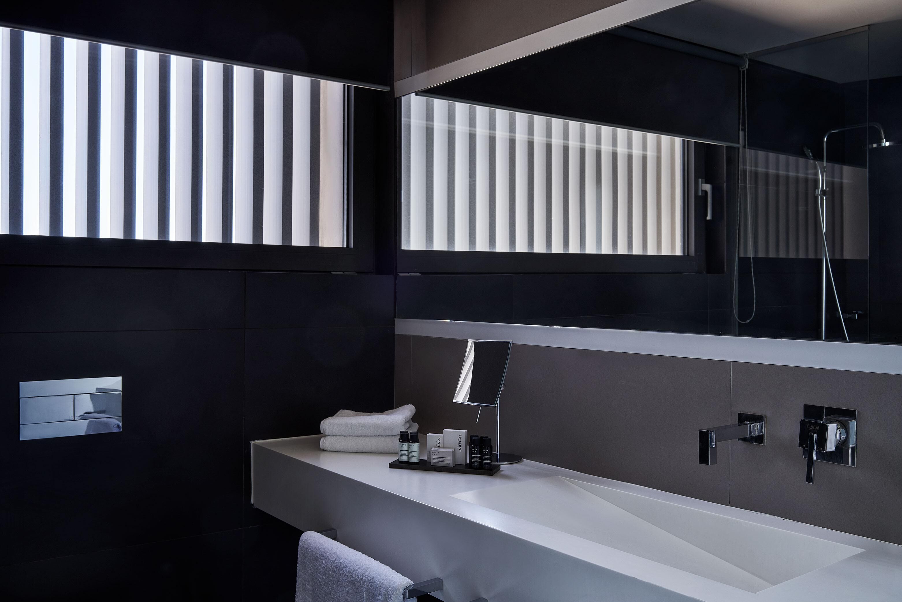 Un baño moderno con un espejo grande, un lavabo blanco y una zona de ducha.