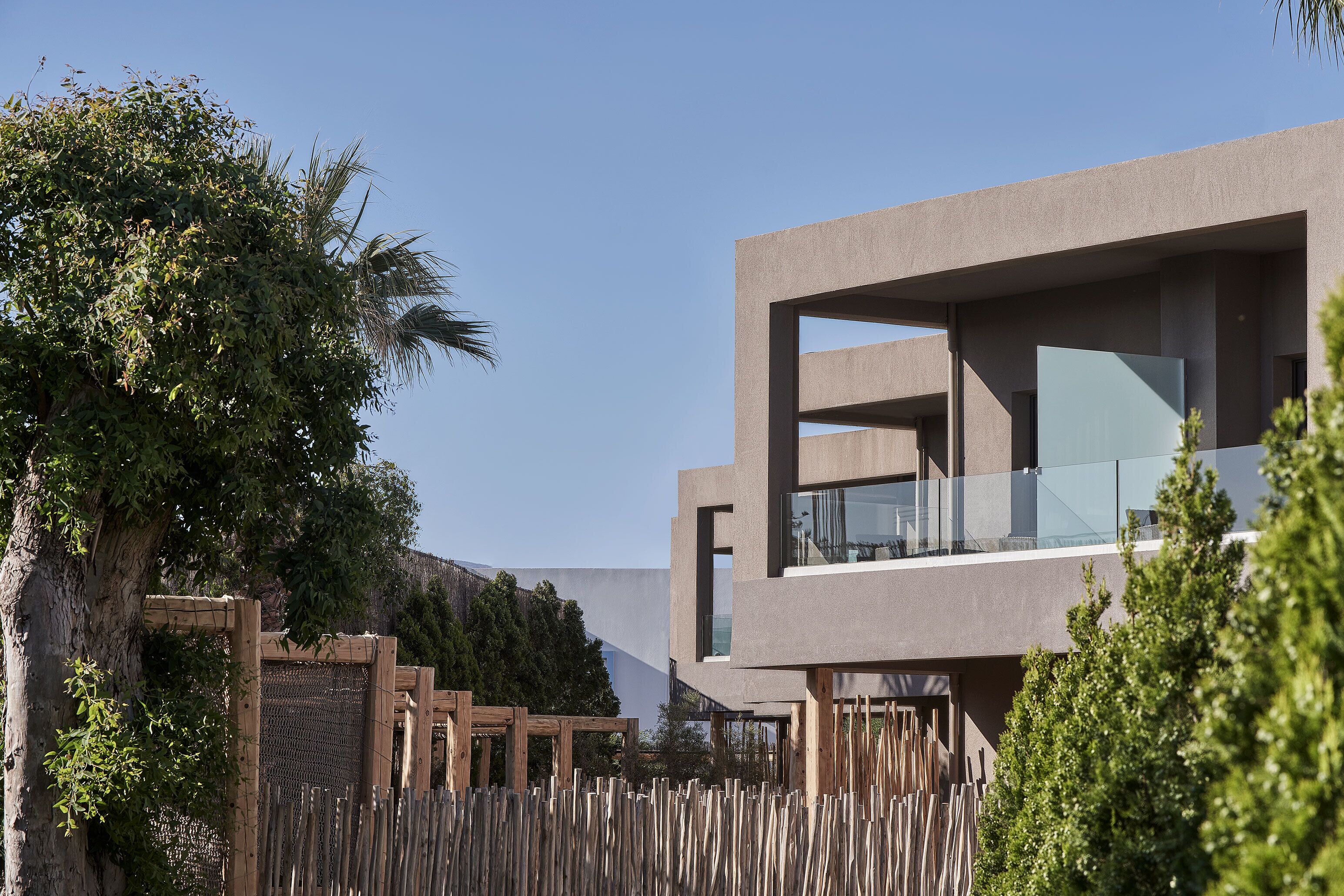 A modern building with a flat roof, large windows, and a wooden fence.
