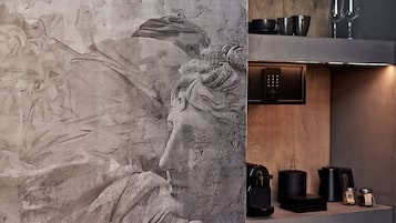 A modern kitchen with a stone wall featuring a relief sculpture, a built-in oven, and a coffee machine.