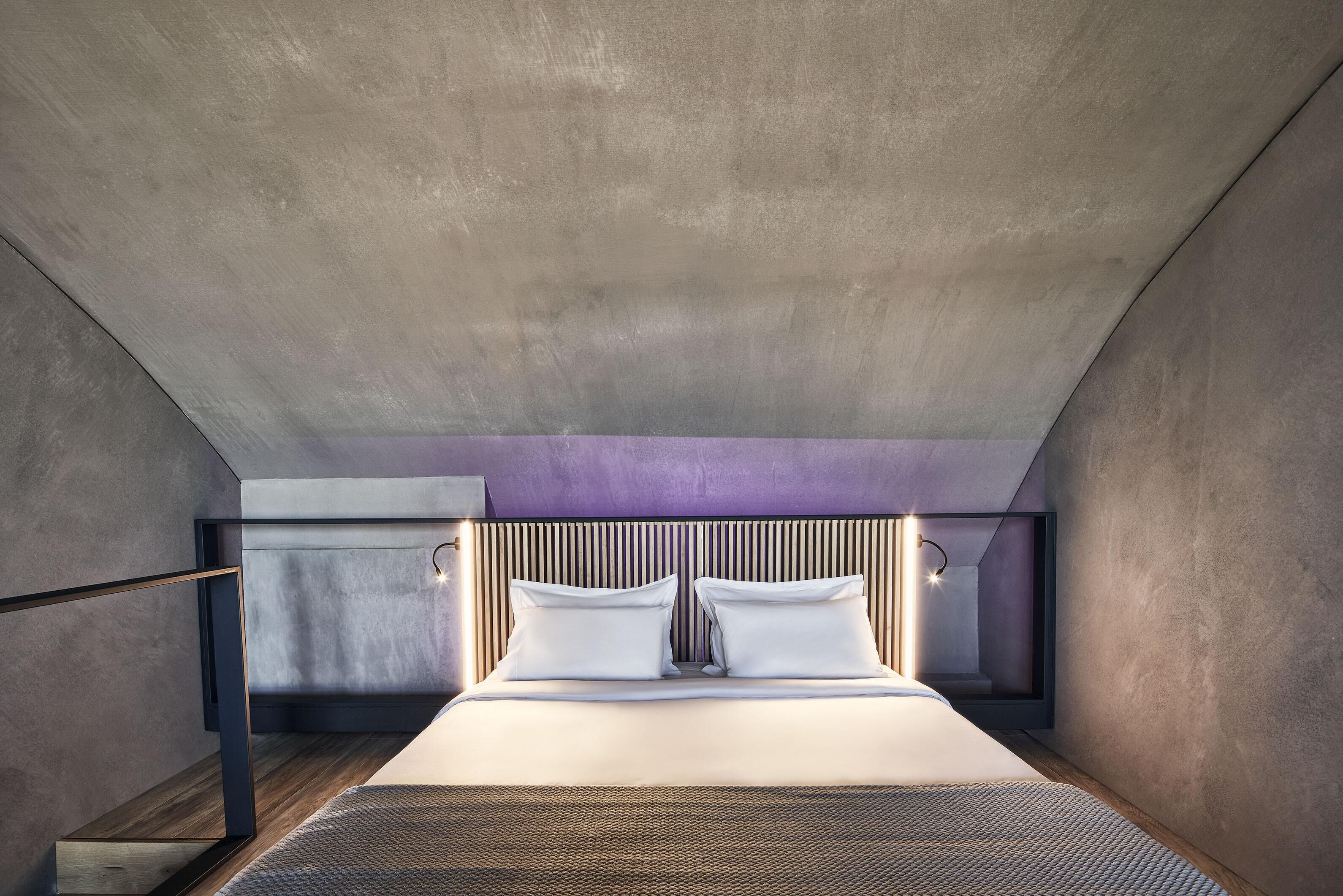 Una camera da letto moderna con un letto grande, un soffitto spiovente e una testiera in legno.