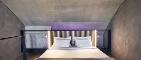 Una camera da letto moderna con un letto grande, un soffitto spiovente e una testiera in legno.