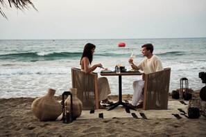 Un espace de restauration aménagé sur la plage, avec une table, des chaises et une vue sur l’océan.