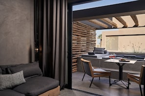 A modern interior with a sofa, a dining table with chairs, and a view of an outdoor patio area. - NEMA Design Hotel & Spa - Small Luxury Hotels of the World (Hersonissos)