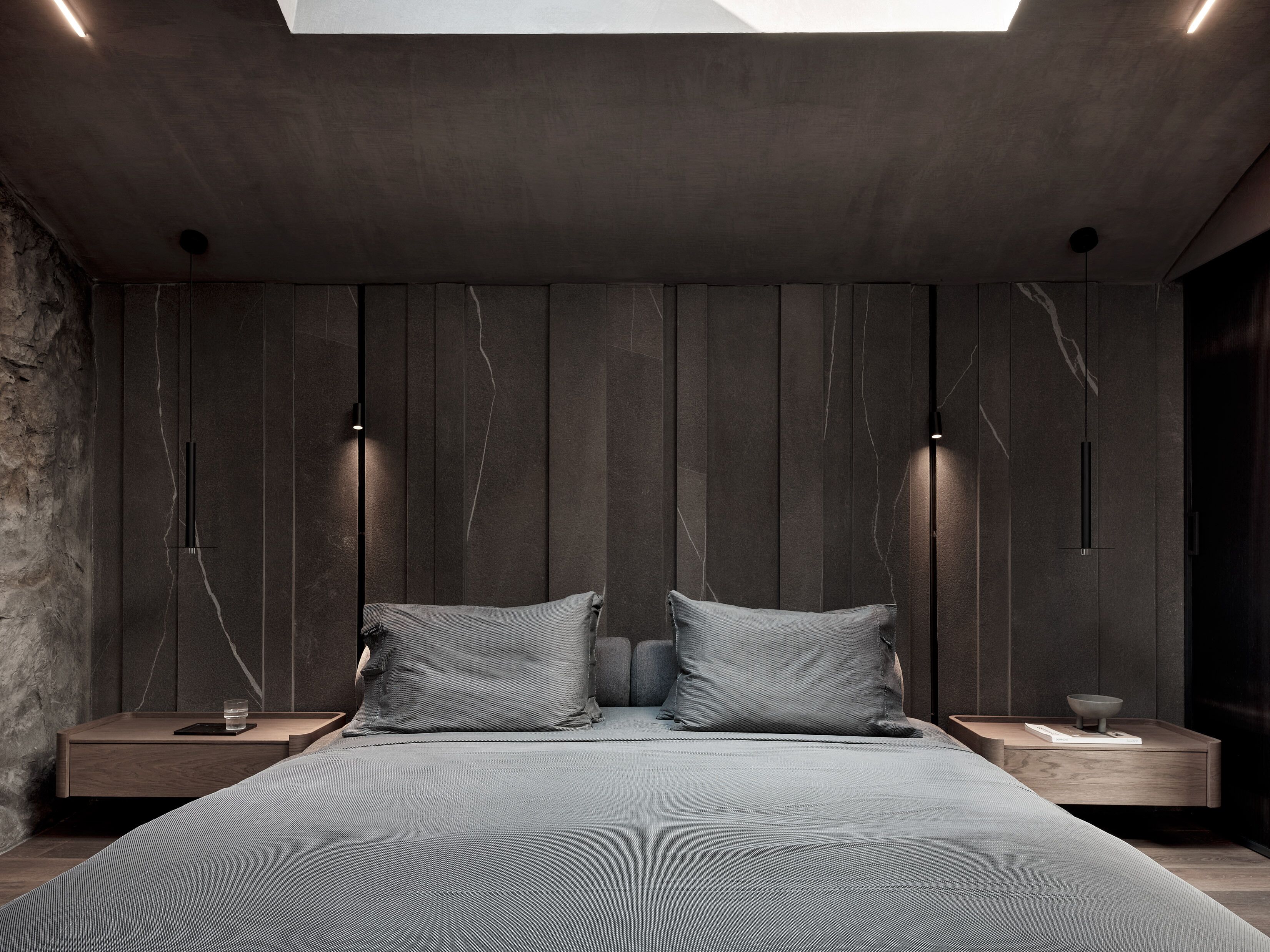 A modern bedroom with a large bed, two bedside tables, and a skylight.