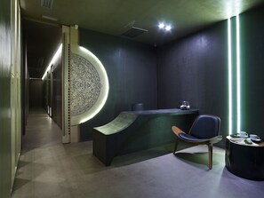 A modern reception desk with a unique circular light feature, a chair, and a small table with a teapot and cups. - NEMA Design Hotel & Spa - Small Luxury Hotels of the World (Hersonissos)