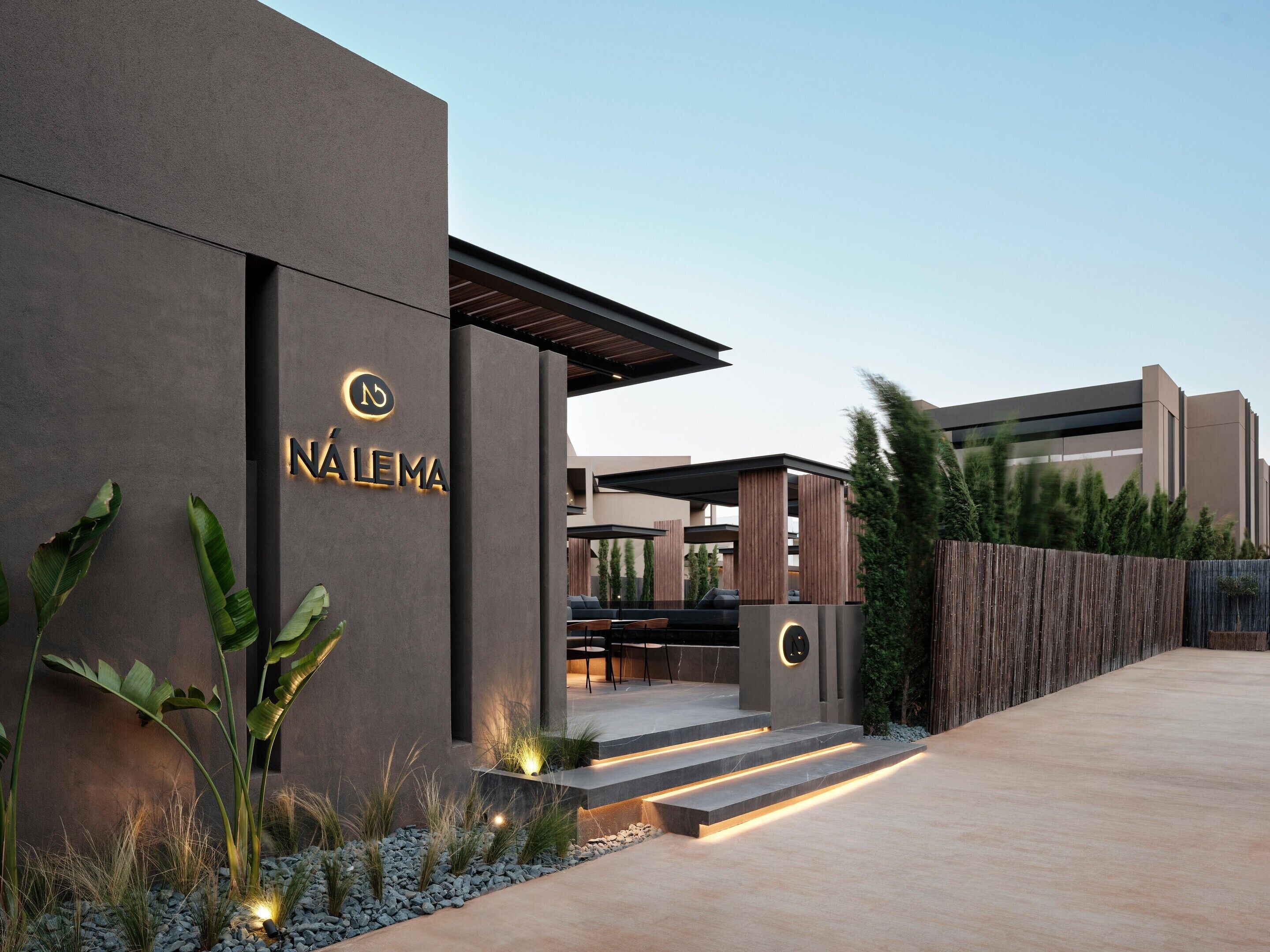 A modern building with a sign reading 'NÁLEMA' and a covered outdoor seating area.