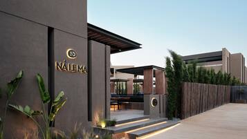A modern building with a sign reading 'NÁLEMA' and a covered outdoor seating area.