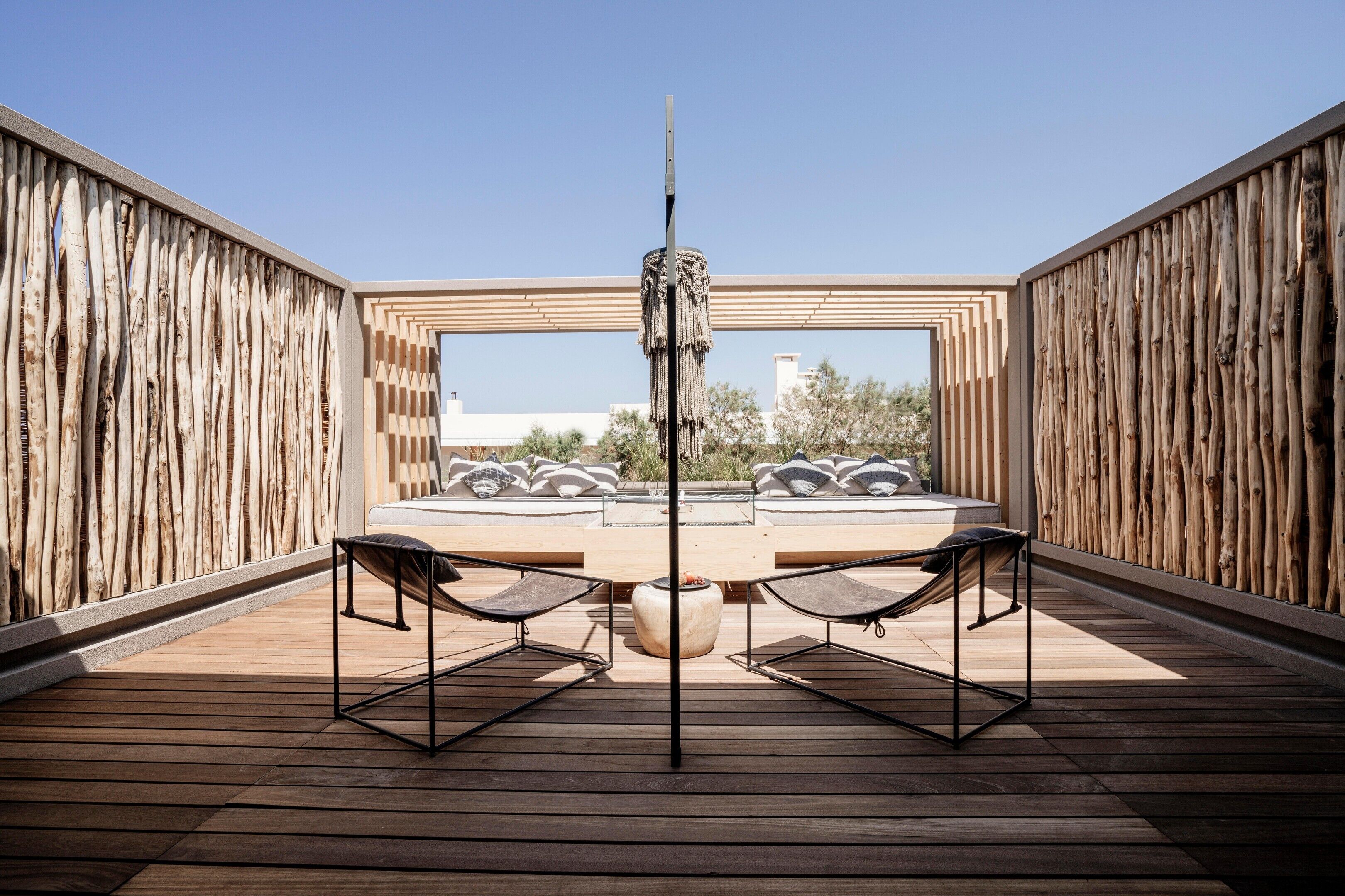 Una terraza en la azotea con una mesa redonda, dos sillas y vistas a edificios distantes.