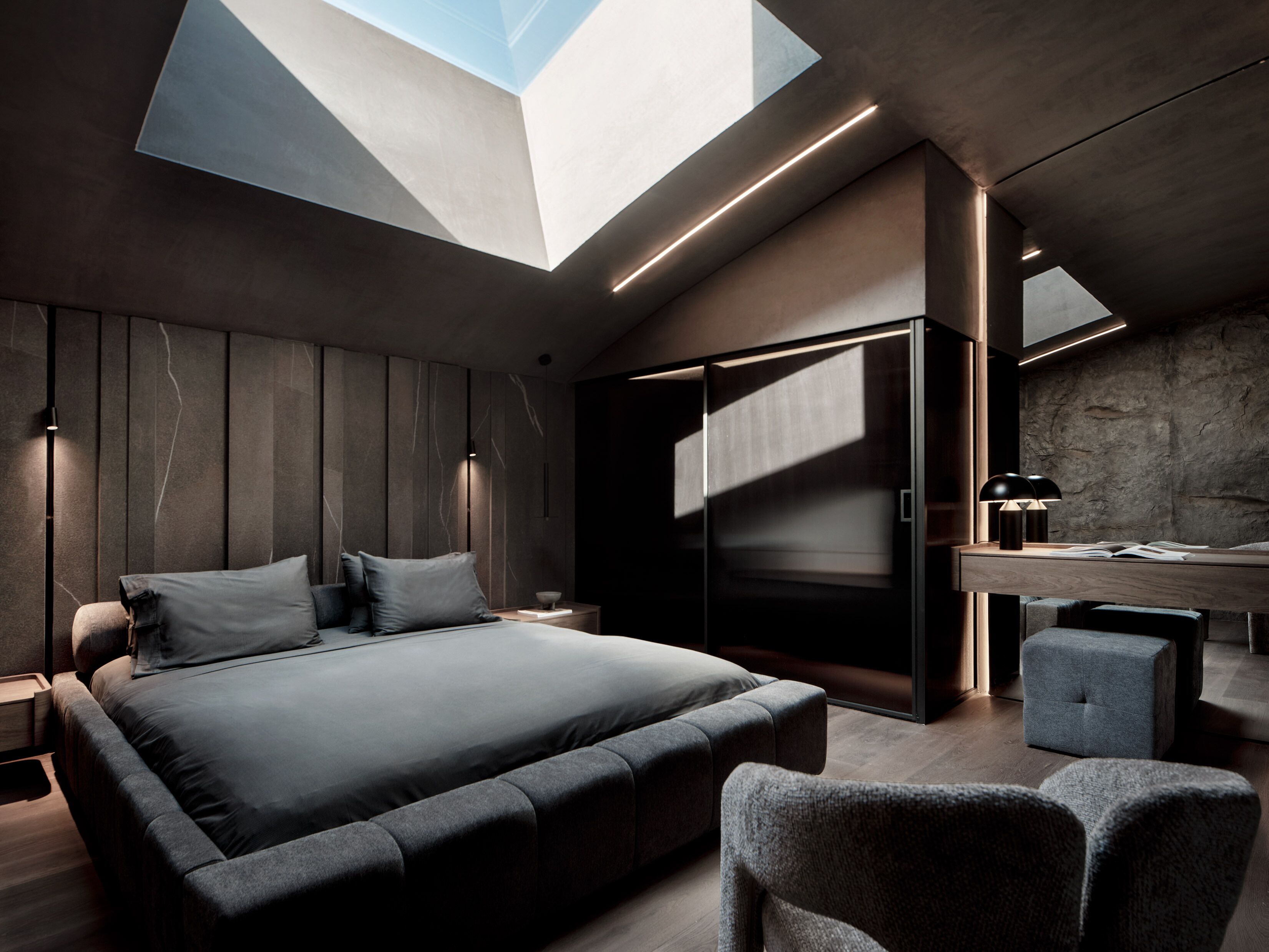 A modern bedroom with a skylight, a bed, a desk, and a chair.