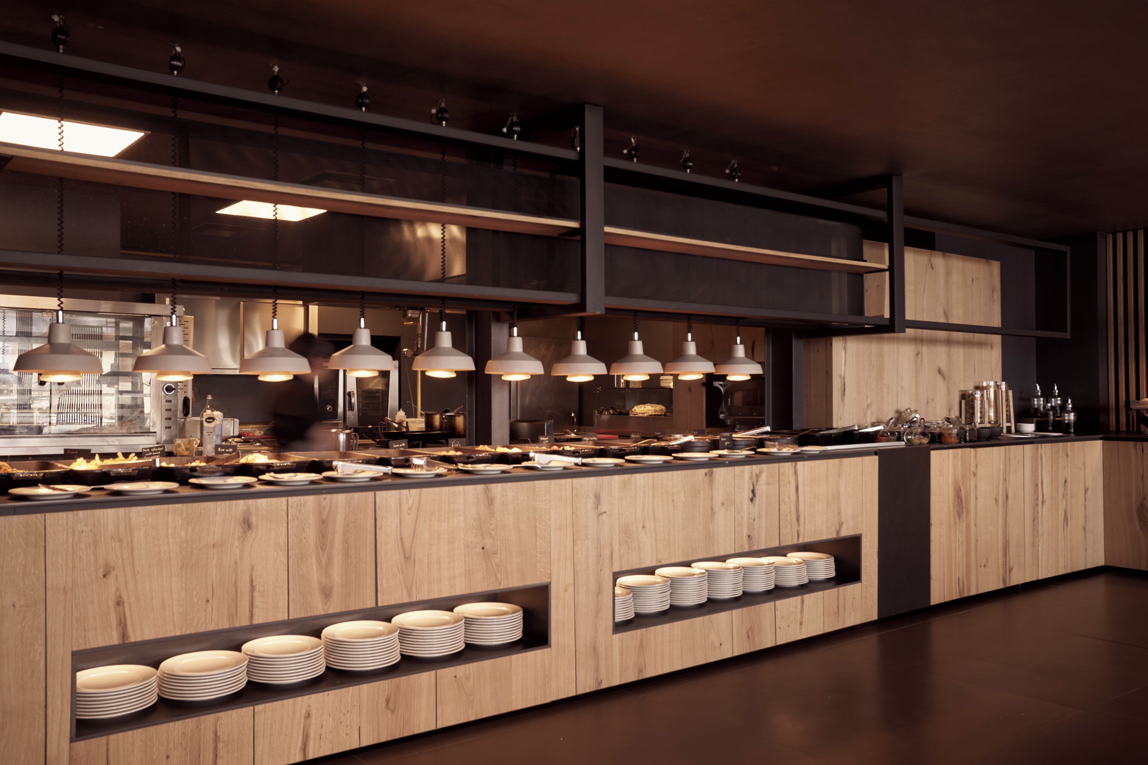 Una cocina moderna con armarios de madera, electrodomésticos de acero inoxidable e iluminación colgante.