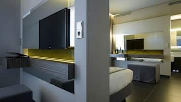 Una habitación de hotel moderna con televisión de pantalla plana, cocina integrada, sofá y cama.
