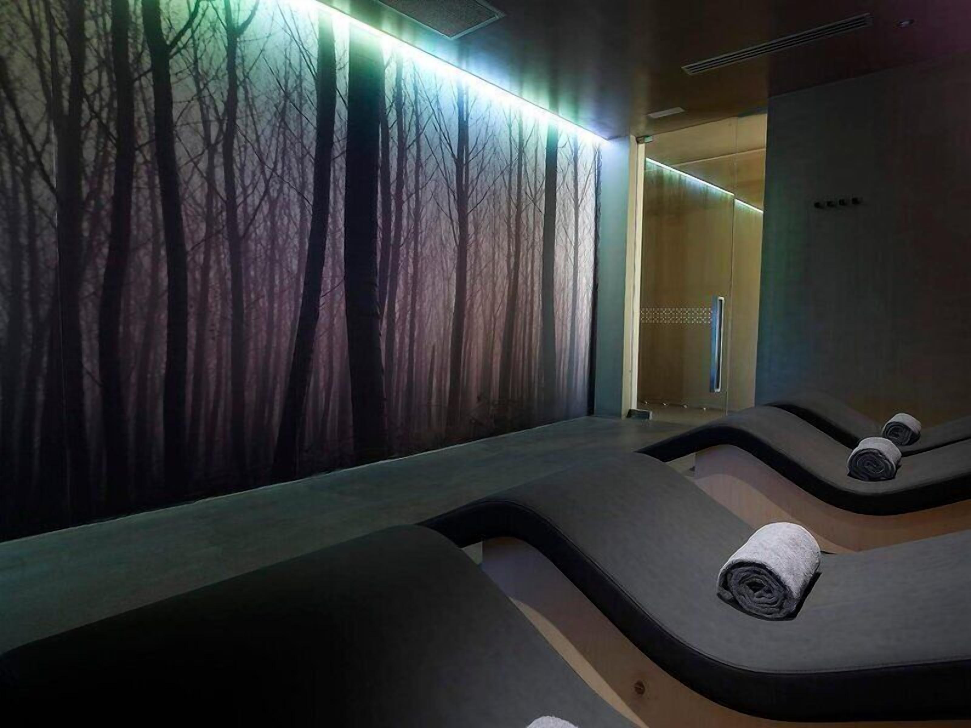 A room with a wall mural of trees, a massage table, and a towel on the table.