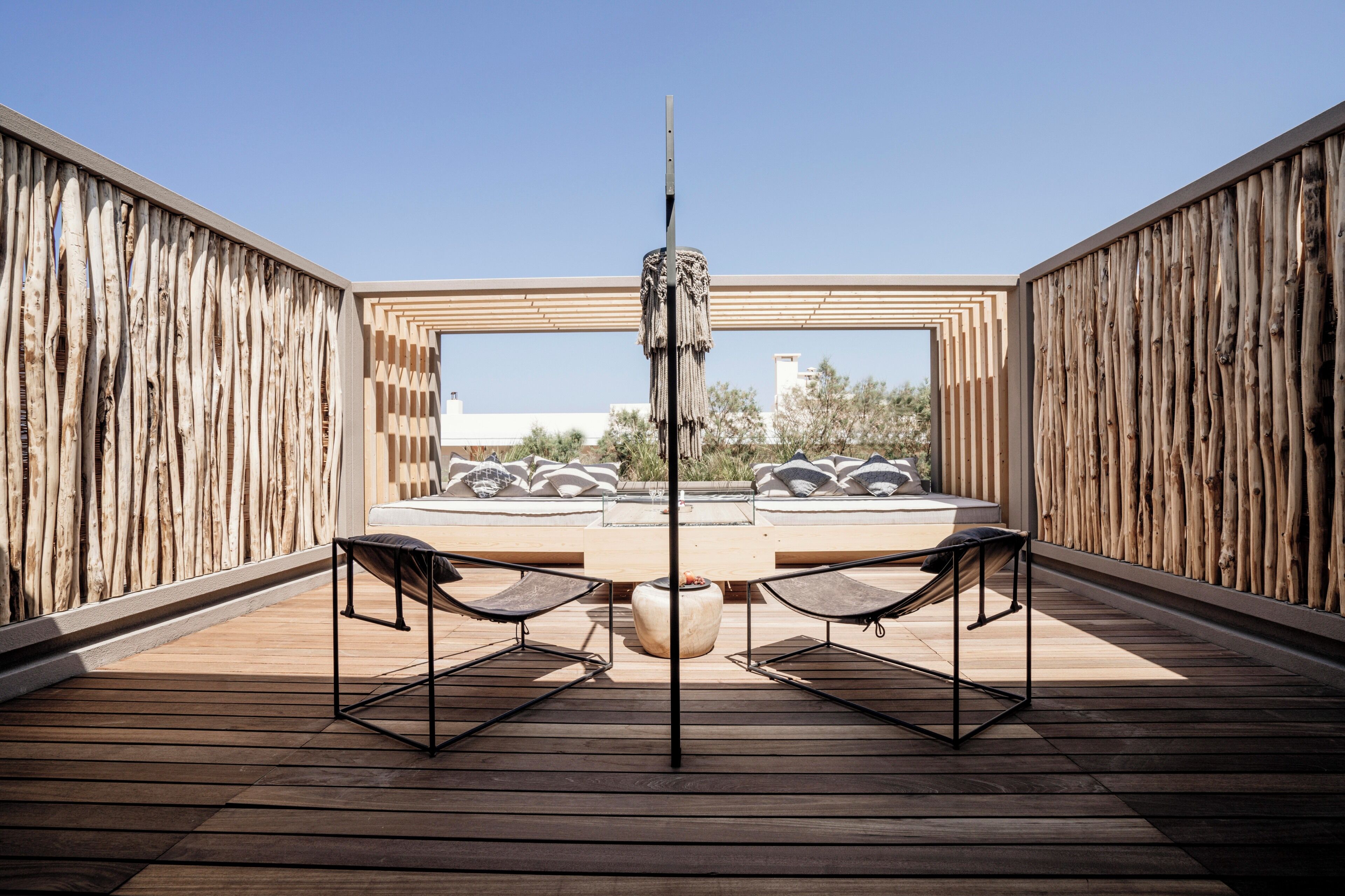 Una terraza al aire libre con una mesa redonda, dos sillas y un poste central.