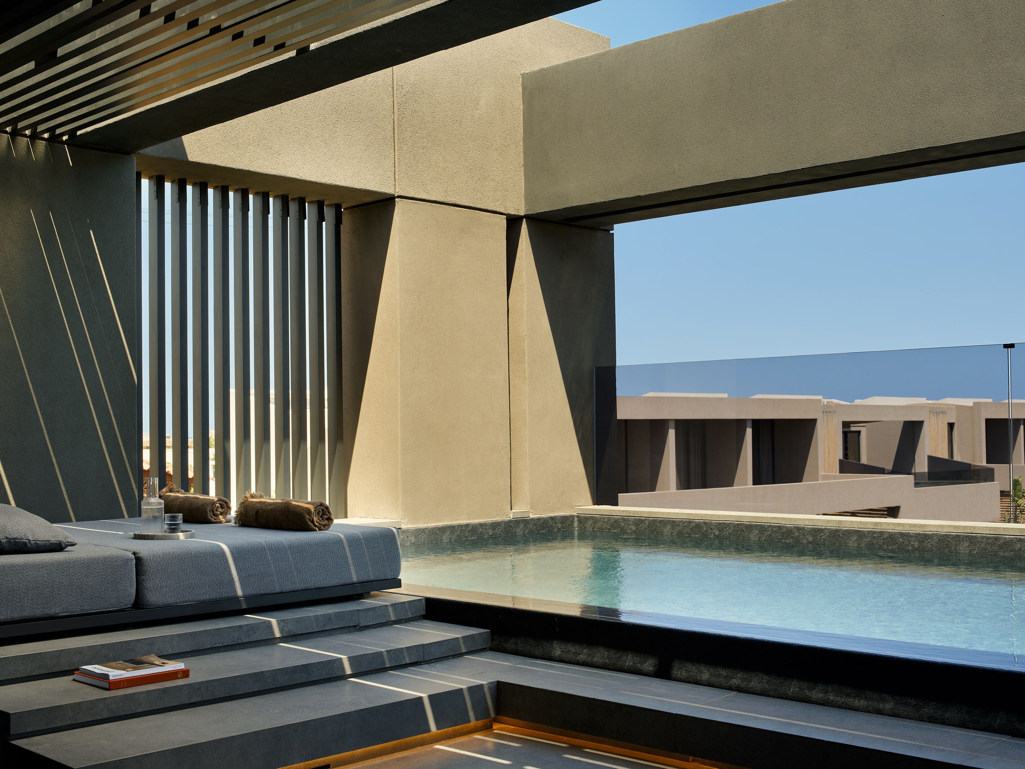 Un interior moderno con piscina, escaleras que conducen a una zona de estar y vistas al exterior.