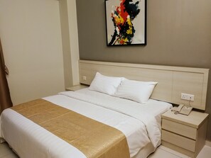 A hotel room with a bed, a bedside table with a phone, and a wall-mounted artwork. - Aurora Hotel (Malacca City)