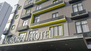 Un hotel de varios pisos con balcones y un cartel que dice 'AURORA HOTEL'.