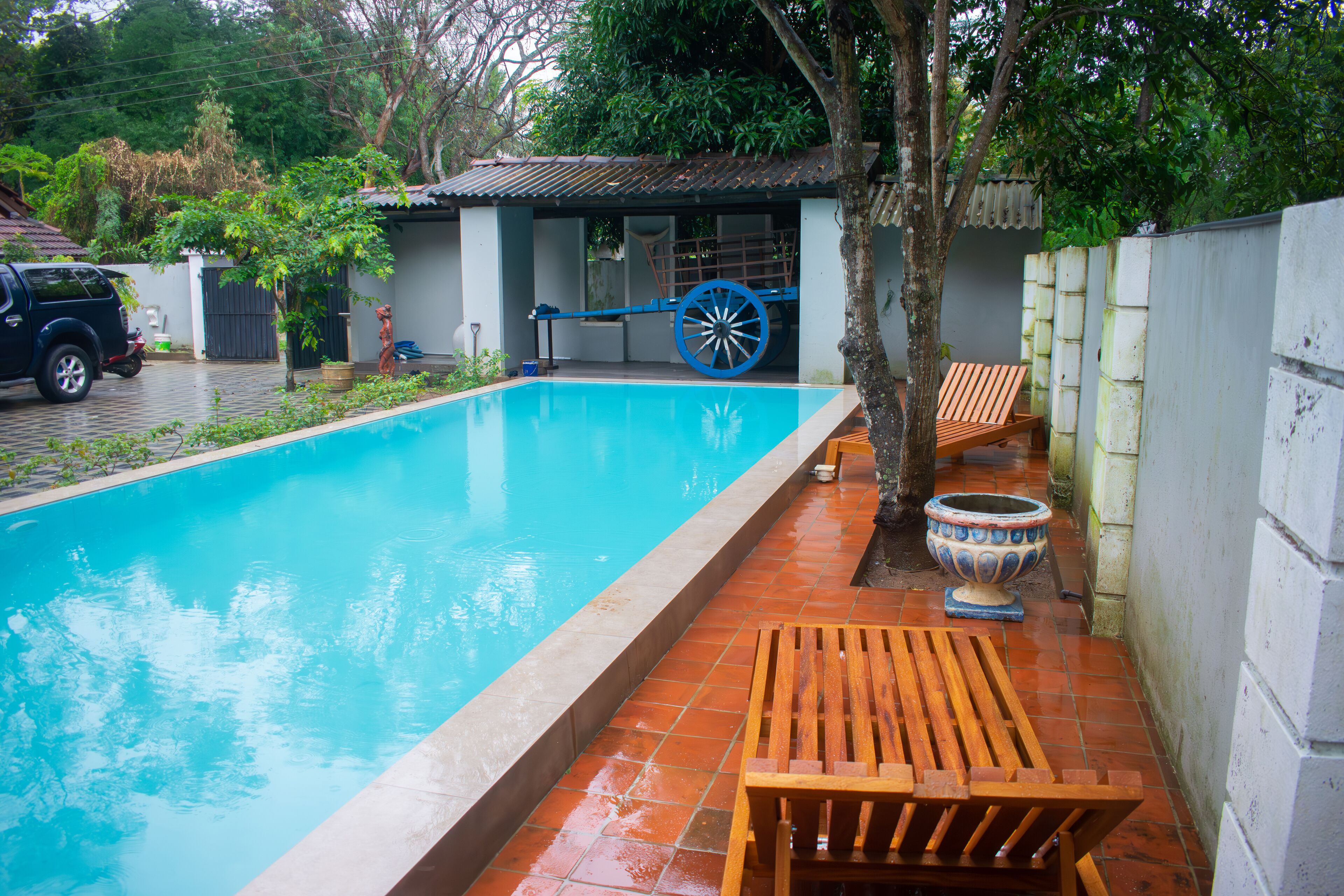 A swimming pool with a wooden bench and a decorative wheelbarrow.