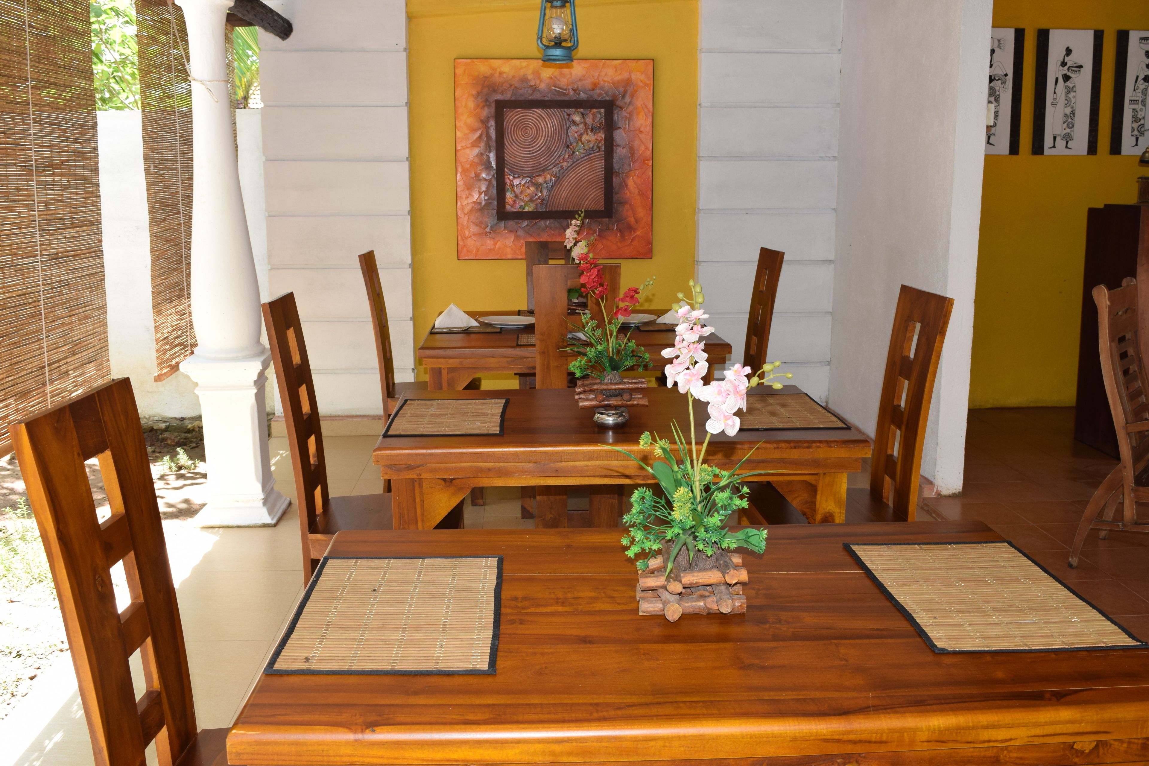 A dining area with wooden tables and chairs, a decorative centerpiece, and artwork on the wall.