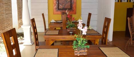 A dining area with wooden tables and chairs, a decorative centerpiece, and artwork on the wall.
